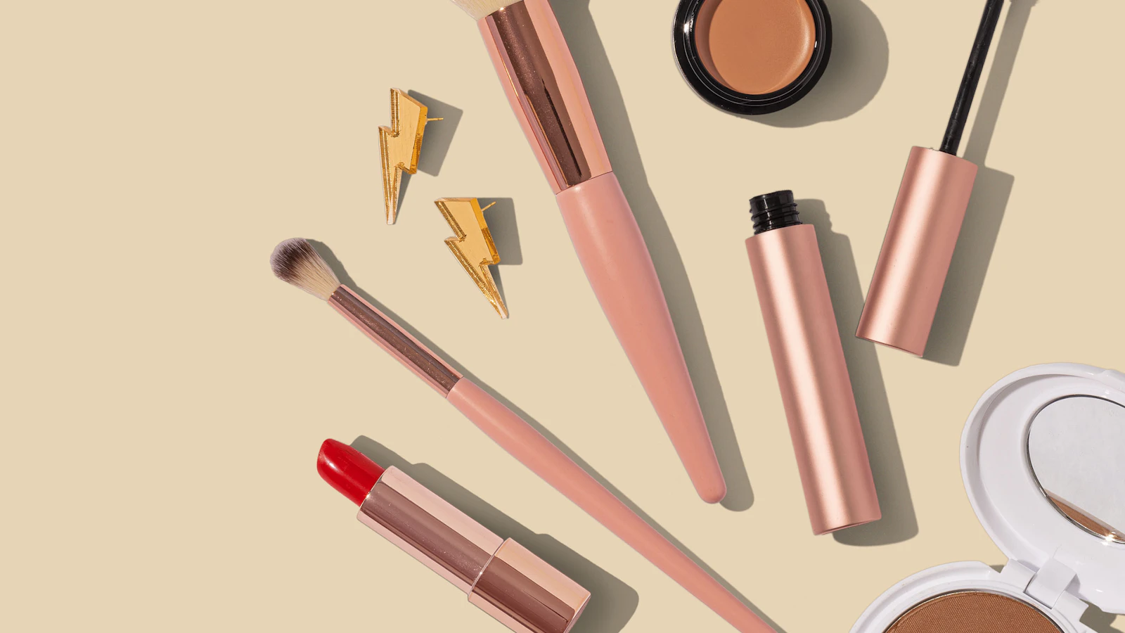 Everyday makeup products arranged neatly on a warm neutral surface