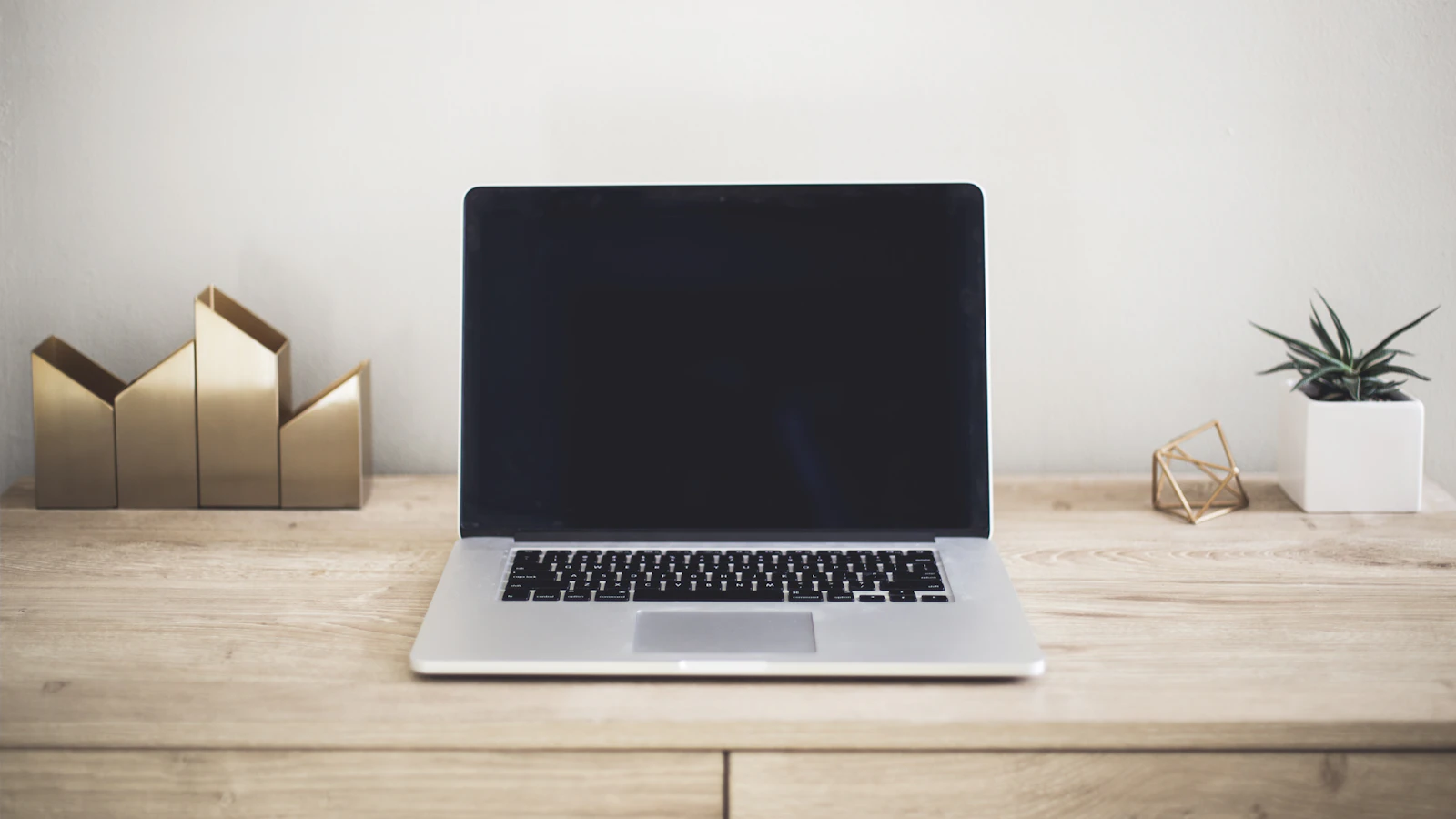 A slim laptop on a calm wood desk in a home workspace